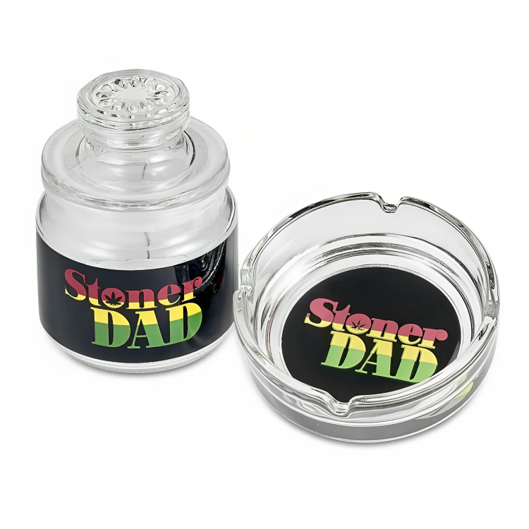A glass ashtray with a sticker that says "stoner dad" - a humorous reference to a father who enjoys cannabis