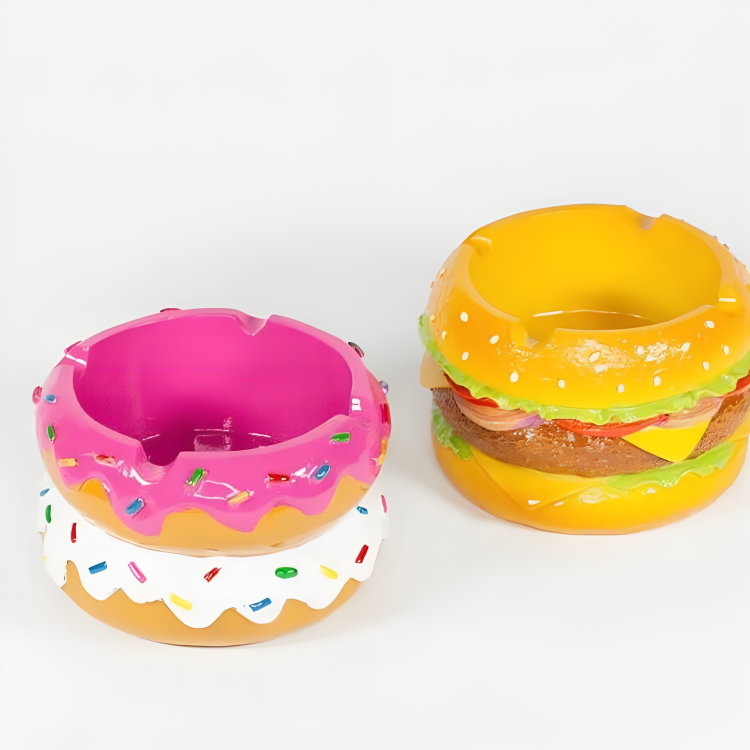 Two plastic hamburgers and a donut on a white surface